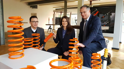 Bürgermeister Prof. Dr. Christoph Landscheidt, Jennifer Maas und Dieter Tenhaeff vor Fahrwerksteilen der maas group