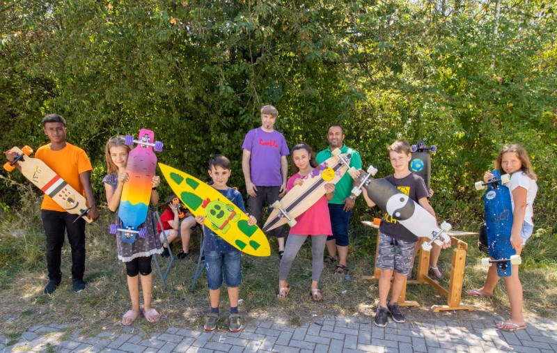 Kinder zeigen ihre selbstgebauten Longboards