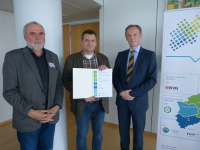 Leiter der Geschäftsstelle „Zukunftsnetzes Mobilität NRW“ Theo Jansen (links) und Staatssekretär Hendrik Schulte (rechts) beglückwünschen Axel Witzke (mittig) zur bestandenen Mobilitätsmanager-Prüfung