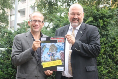 Das Bild zeigt den 1. Beigeordneten der Stadt Kamp-Lintfort Dr. Christoph Müllmann mit Bereichsleiter TÜV Nord Bildung Thomas Ossenkopp bei der Präsentation des Plakates.